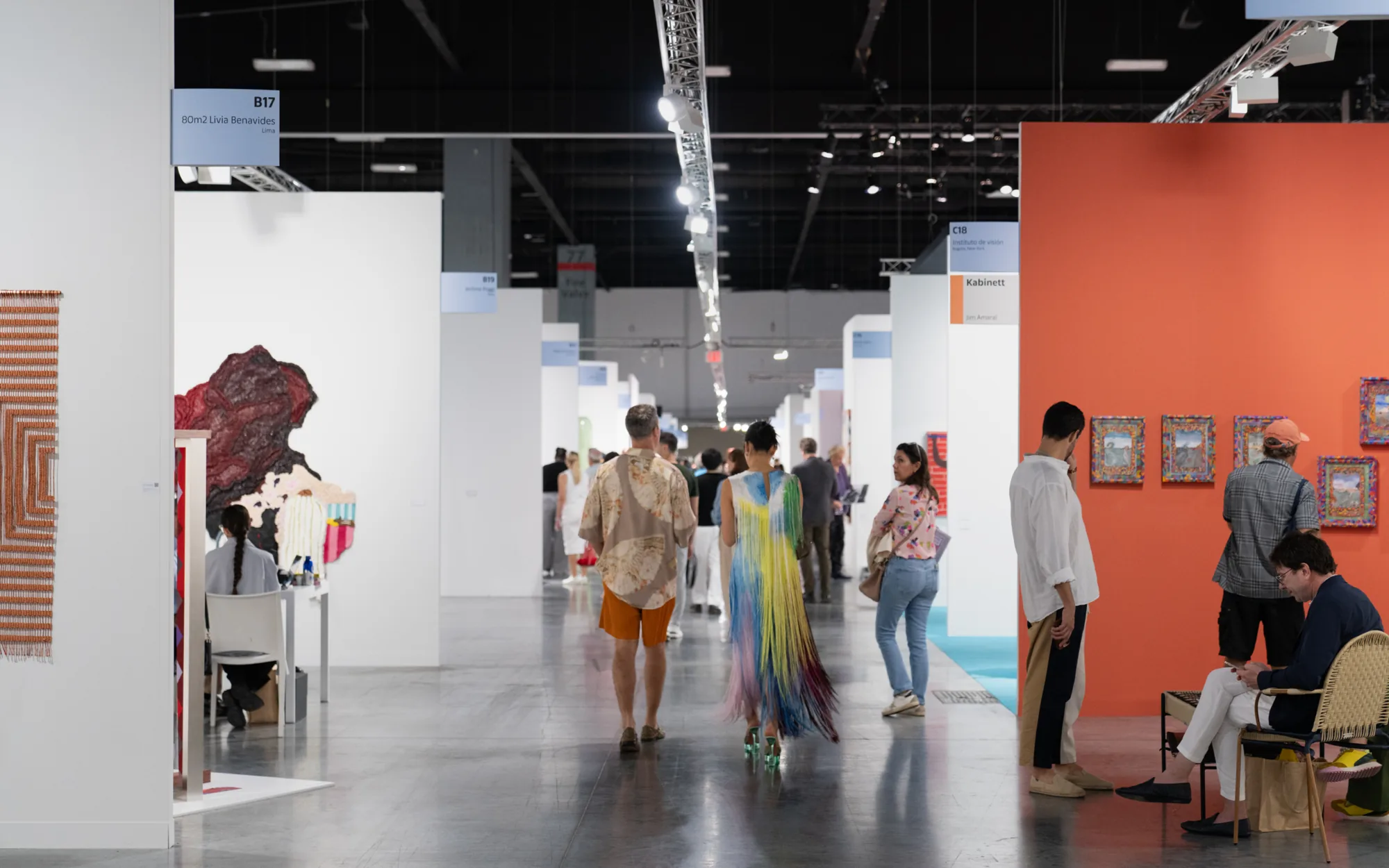 Visitors walking an aisle of gallery booths from Lima and Bogotá at Art Basel Miami Beach