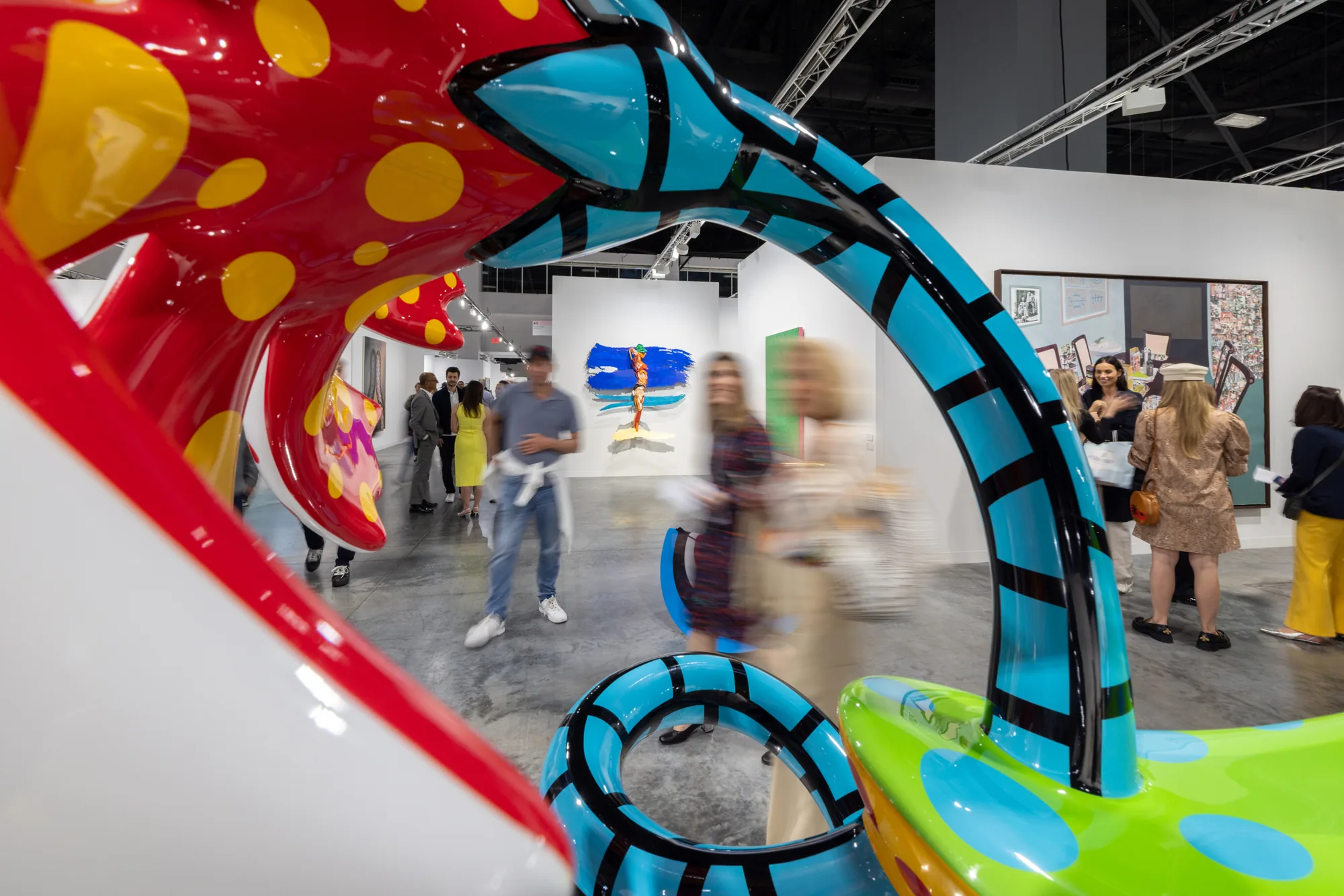 Visitors seen through a brightly painted sculpture on the fair floor at Art Basel Miami Beach