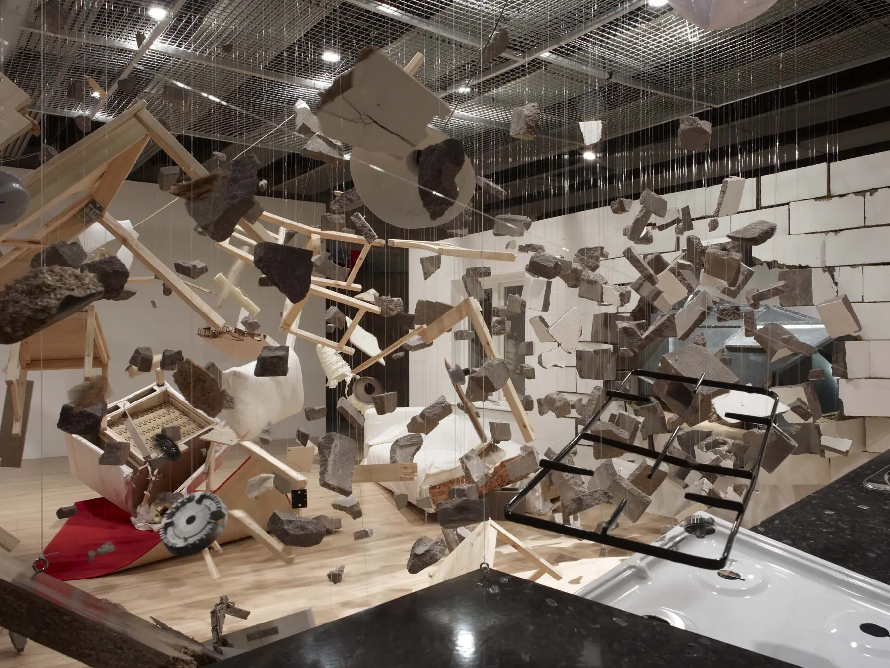 An installation by Los Carpinteros in which a room and its furniture hang suspended mid-explosion